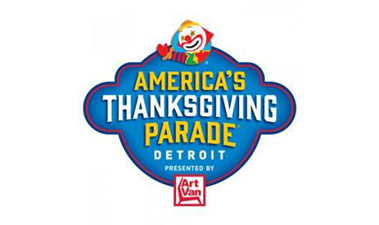 logo for "america's thanksgiving parade" in detroit. features a colorful clown face and states it is presented by art van. the design includes bold blue, yellow, and red colors.