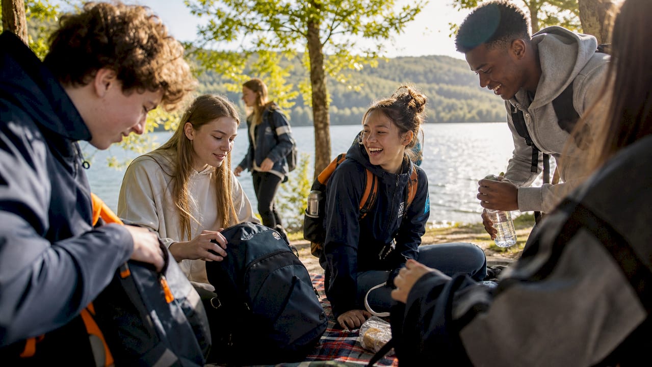 high school students packing backpacks outdoors