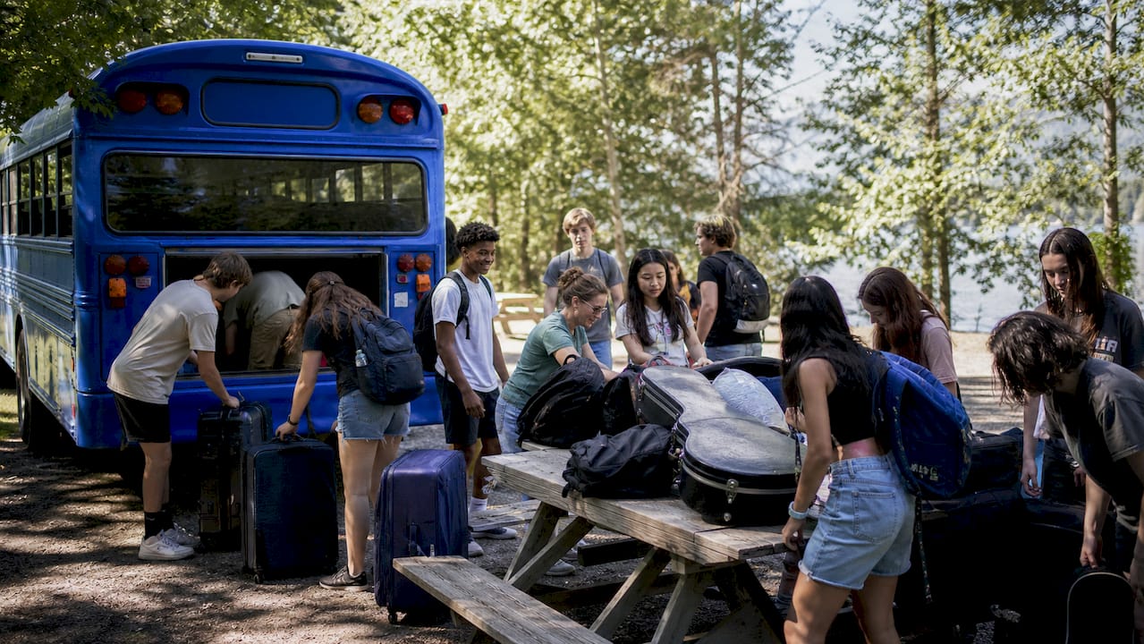 students loading luggage onto bus for trip