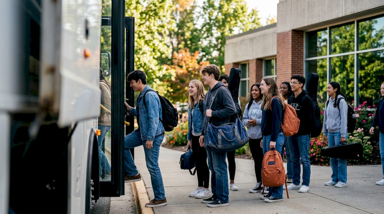 high school students boarding charter bus with luggage