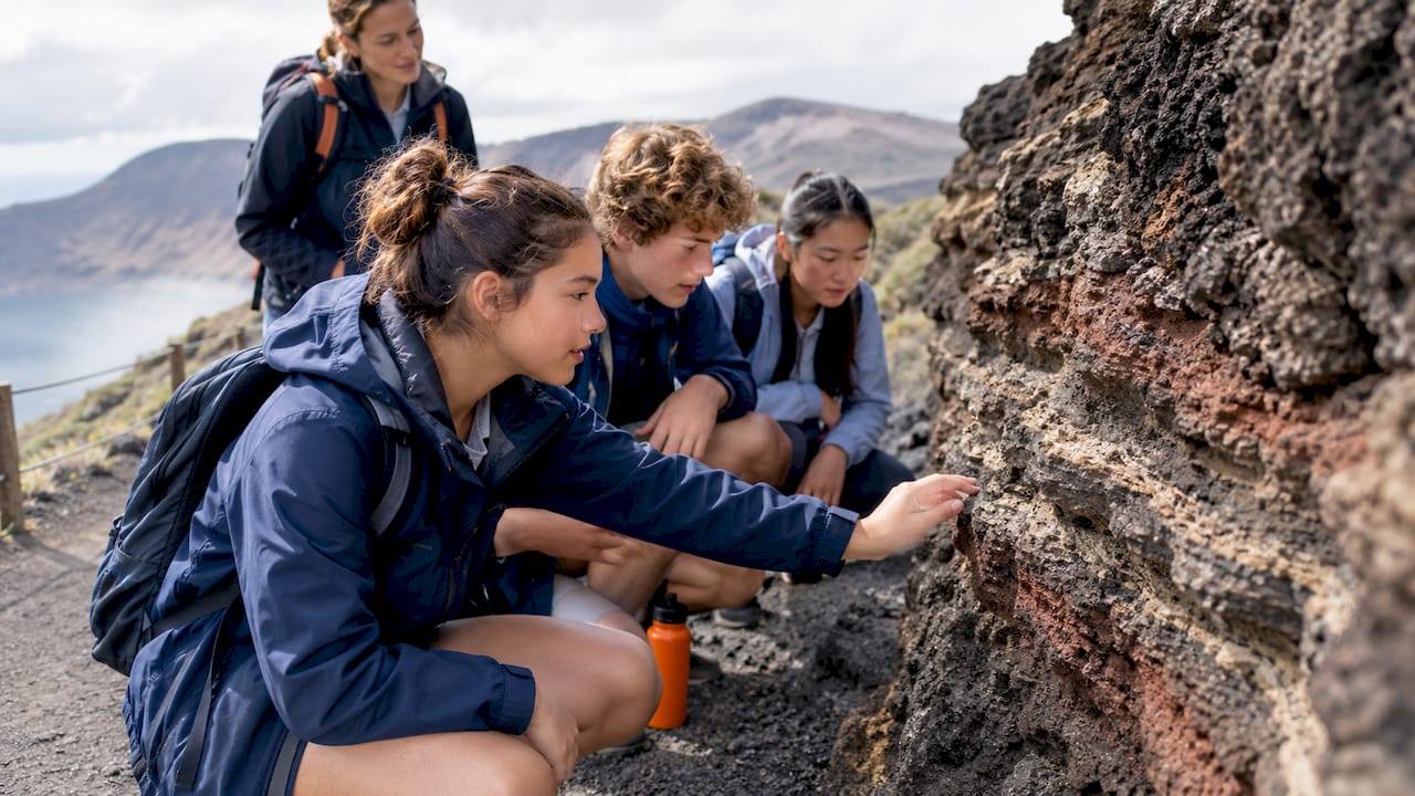 Students studying volcanic rock on a field trip